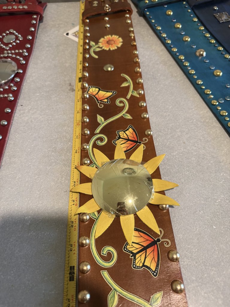 Measuring a hand-tooled monarch belt on the workbench